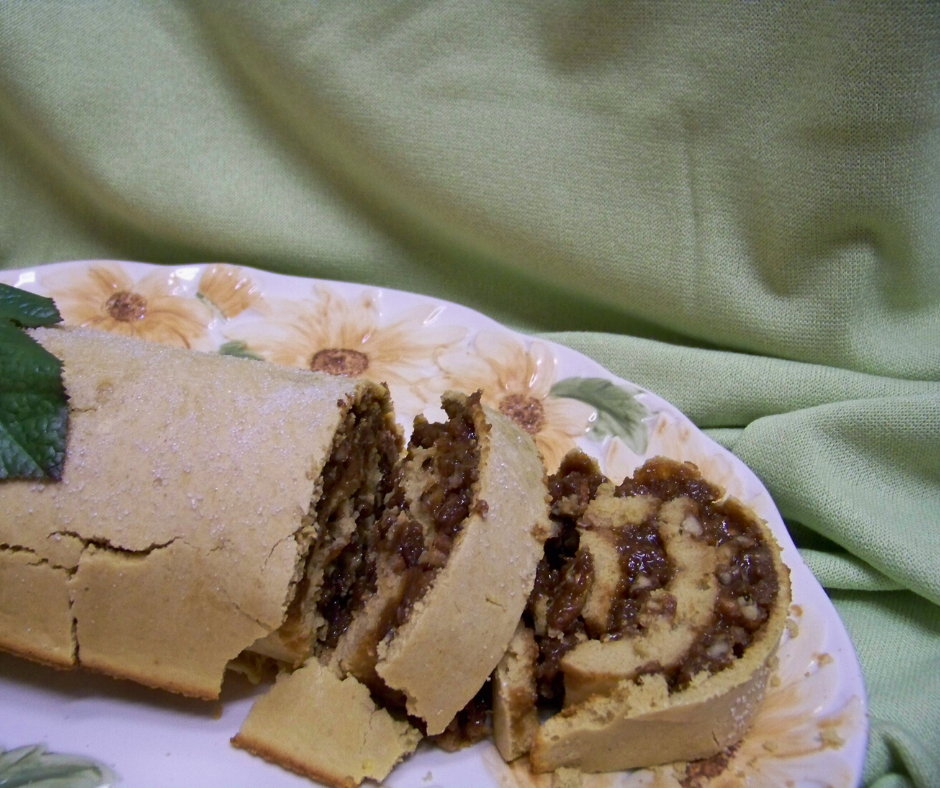 Pecan Pie Cake Roll sliced on a platter with a sage green background