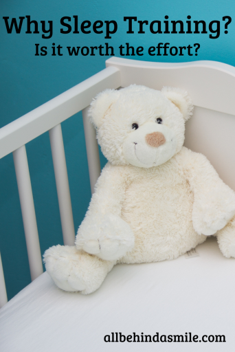 Blue wall behind a white crib with a white bear and white sheet with text Why Sleep Training - Is it worth the effort?